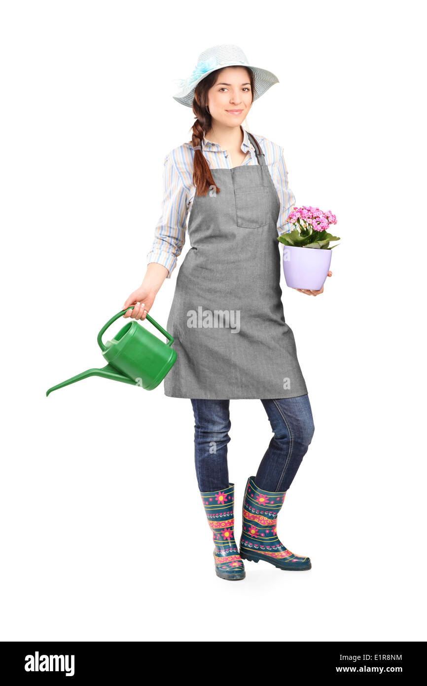 Full length portrait of a female gardener holding a watering can and a ...