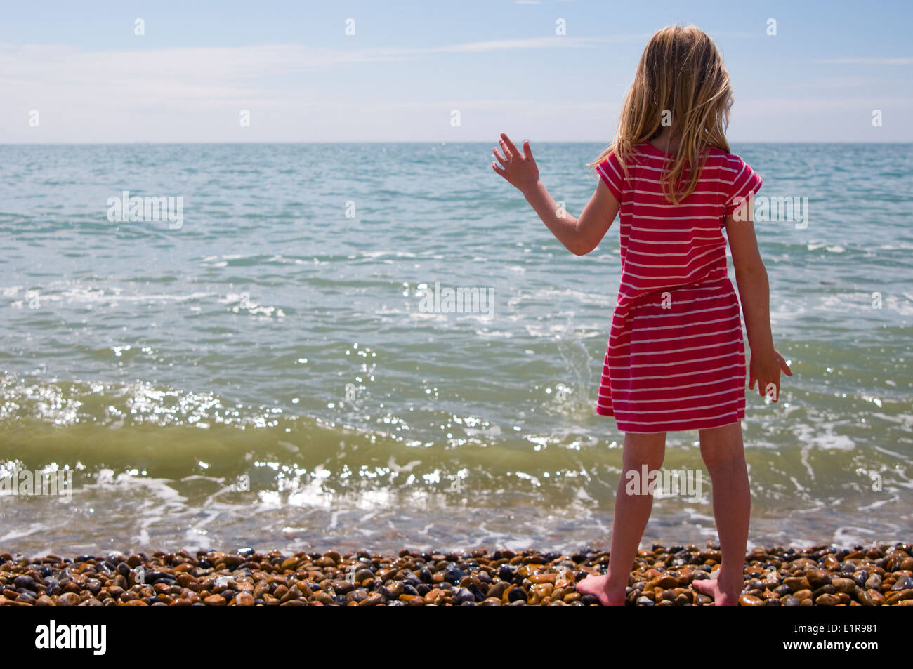 young girl standing by the sea on a beautiful sunny day Stock Photo