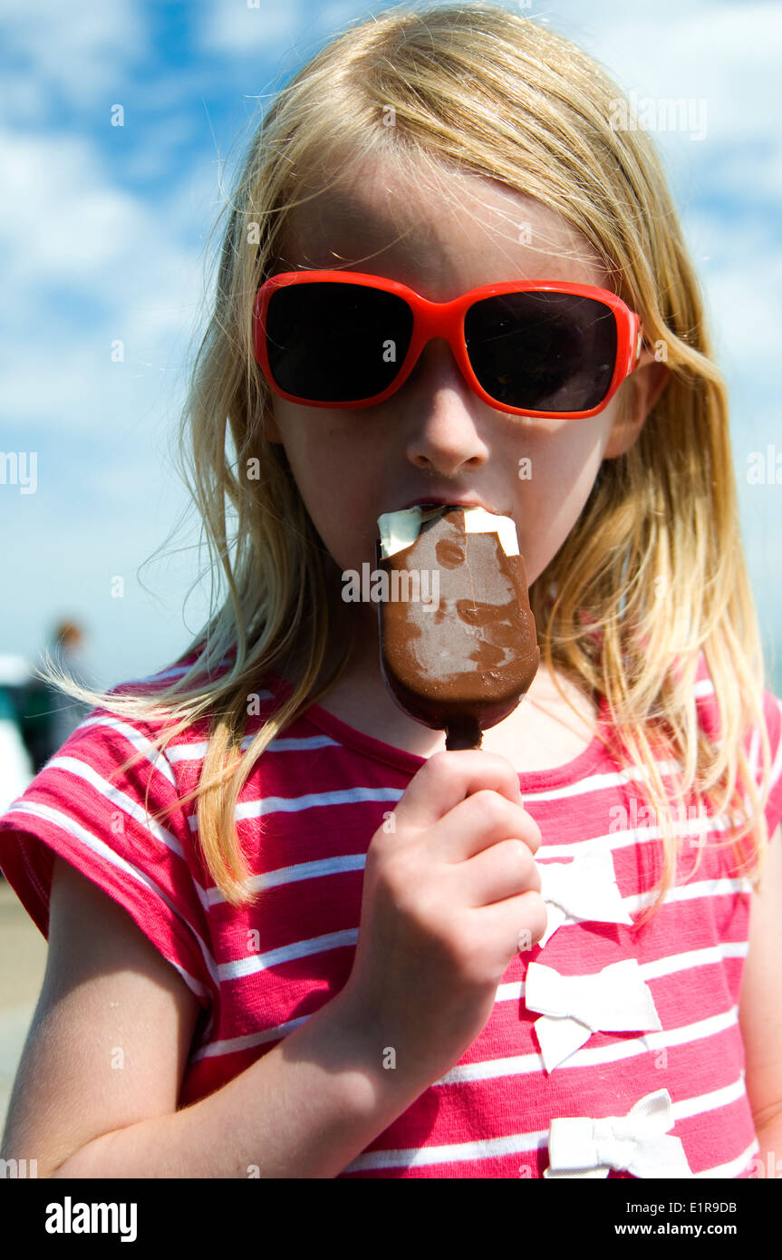 Young girl enjoying a chocolate ice cream on a hot sunny day in summer Stock Photo