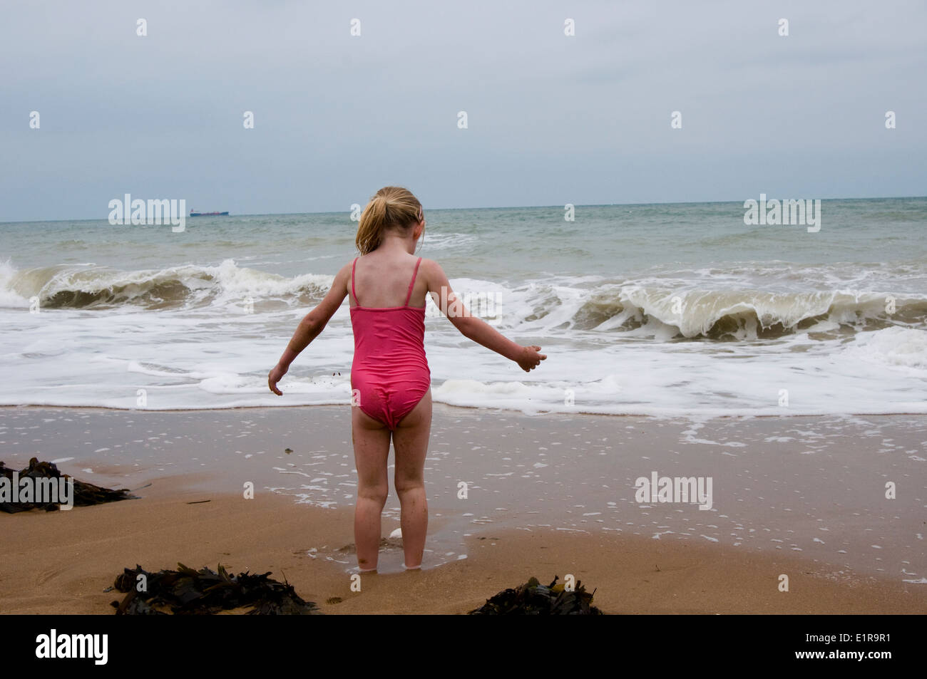 young girl sinking in the sand on a dull summer's day in U.K. Stock Photo