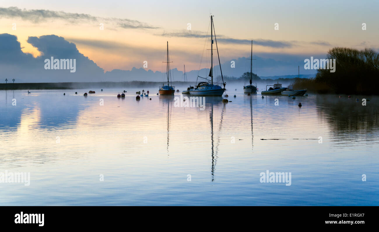A misty sunrise at over boats moored at the quay in Christchurch in Dorset Stock Photo