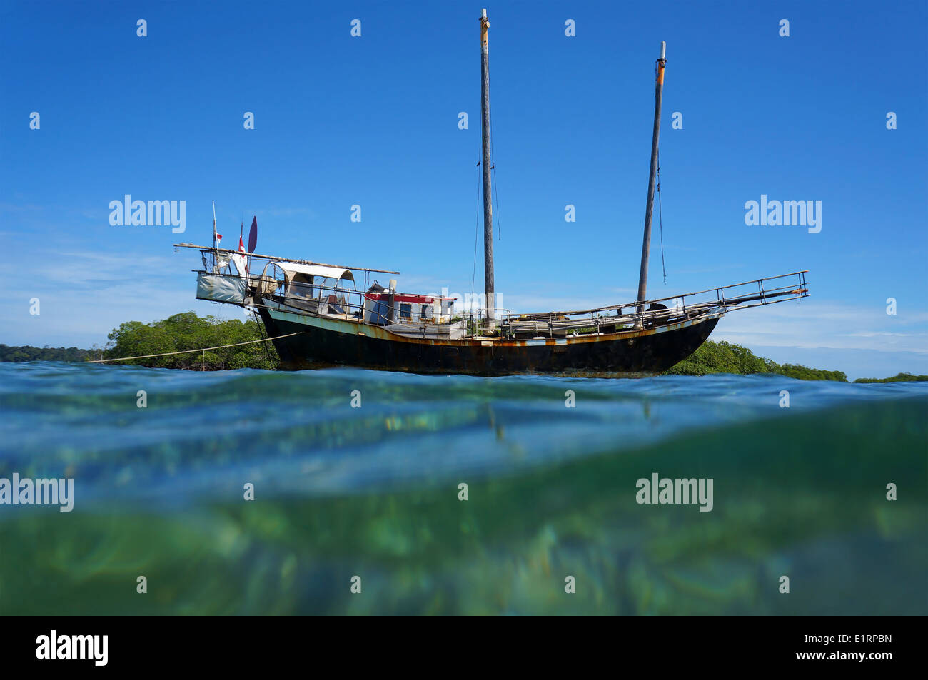 Old sailing boat stranded on a shallow reef, viewed from water surface, Caribbean sea Stock Photo
