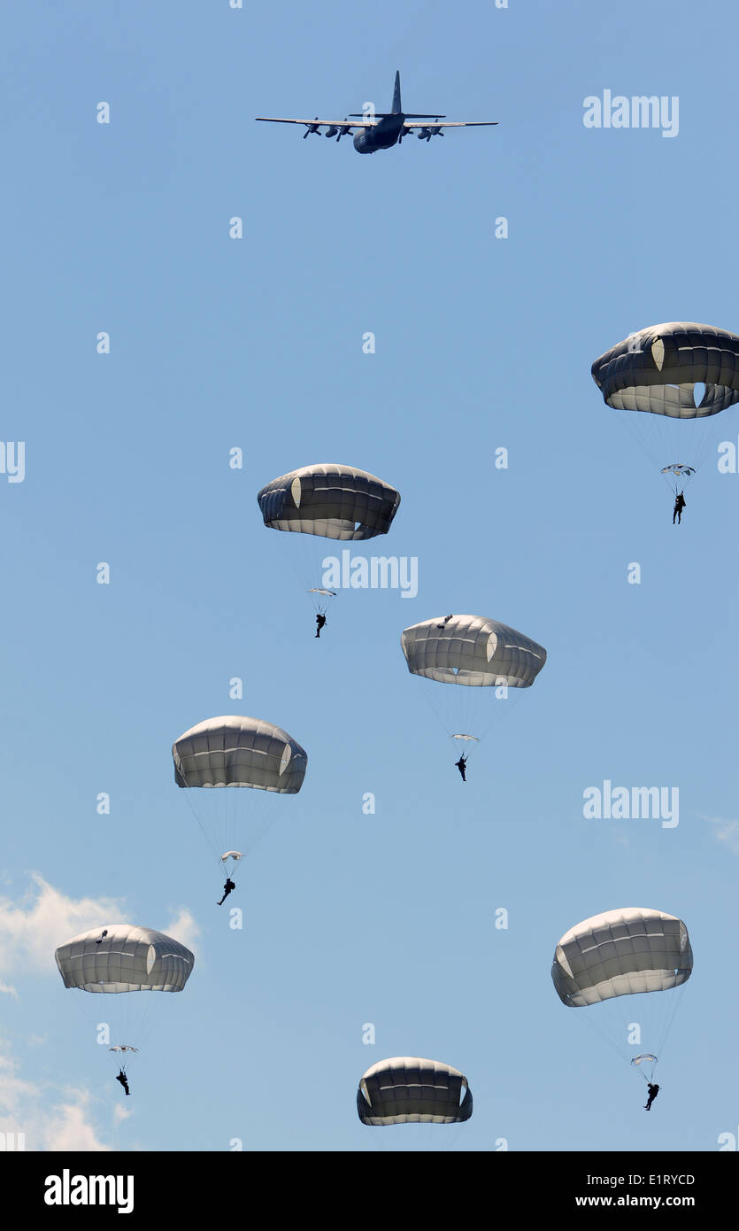 US and International army paratroopers parachute from a C-130 Hercules aircraft to commemorate the 70th anniversary of D-Day June 8, 2014 in Normandy, France. Over 700 paratroopers from the United States, France, Germany, England and the Netherlands re-enacted the historic airdrop over the town of Chef-du-Pont, France. Stock Photo