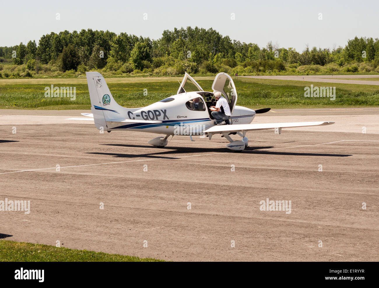 Pilot and passenger with foot on wing going over safety checklist on Cirrus SR20 aircraft at local airport Stock Photo