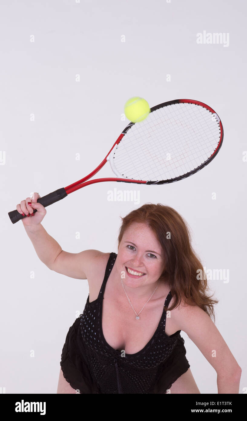 Young tennis player in little black dress hits the ball Stock Photo