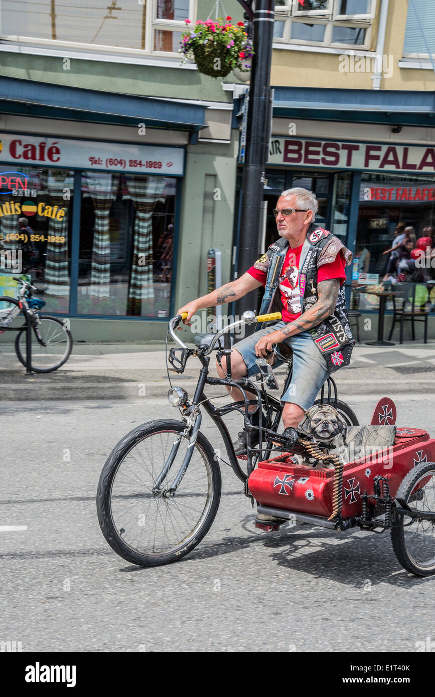 Man on bicycle (Multi-media artist Mad Dog) with punk sidecar with machine gun and helmeted dog, Stock Photo