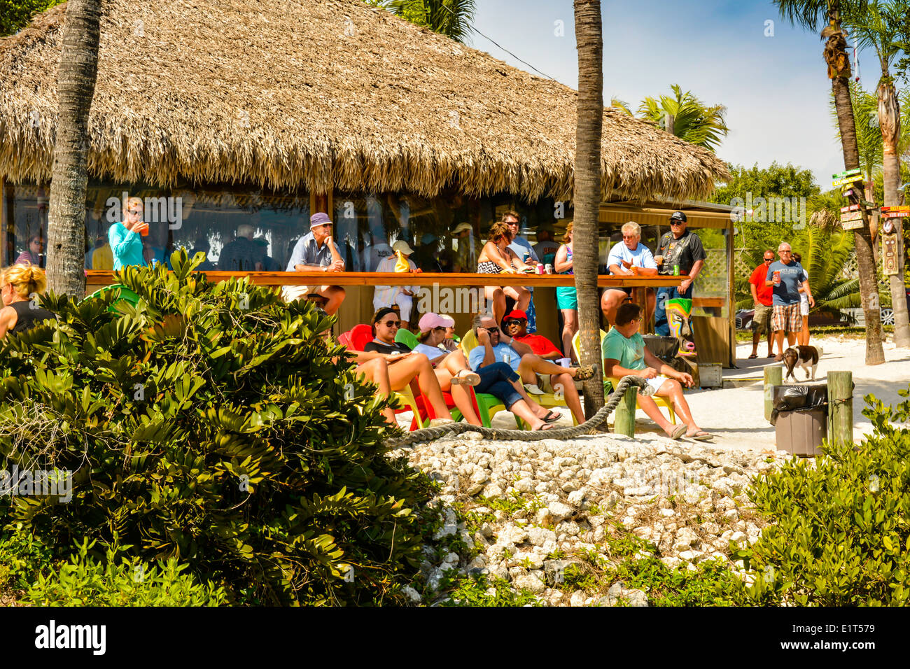 Happy hour in full swing at a thatched roof tiki hut bar amongst