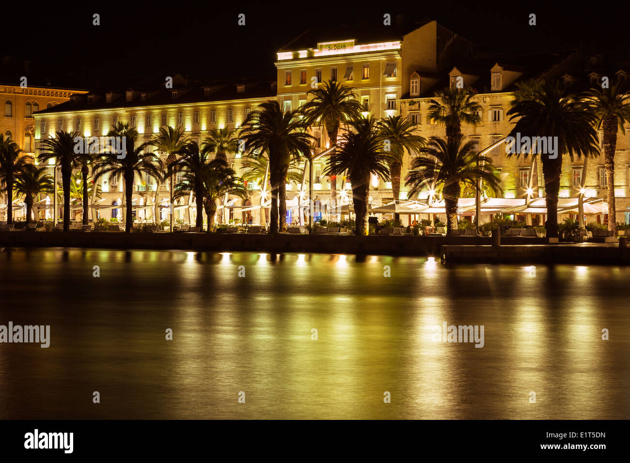 Night-time at the Riva in Split, Croatia. The lights from the cafe bars and restaurants are reflected in the water. Stock Photo
