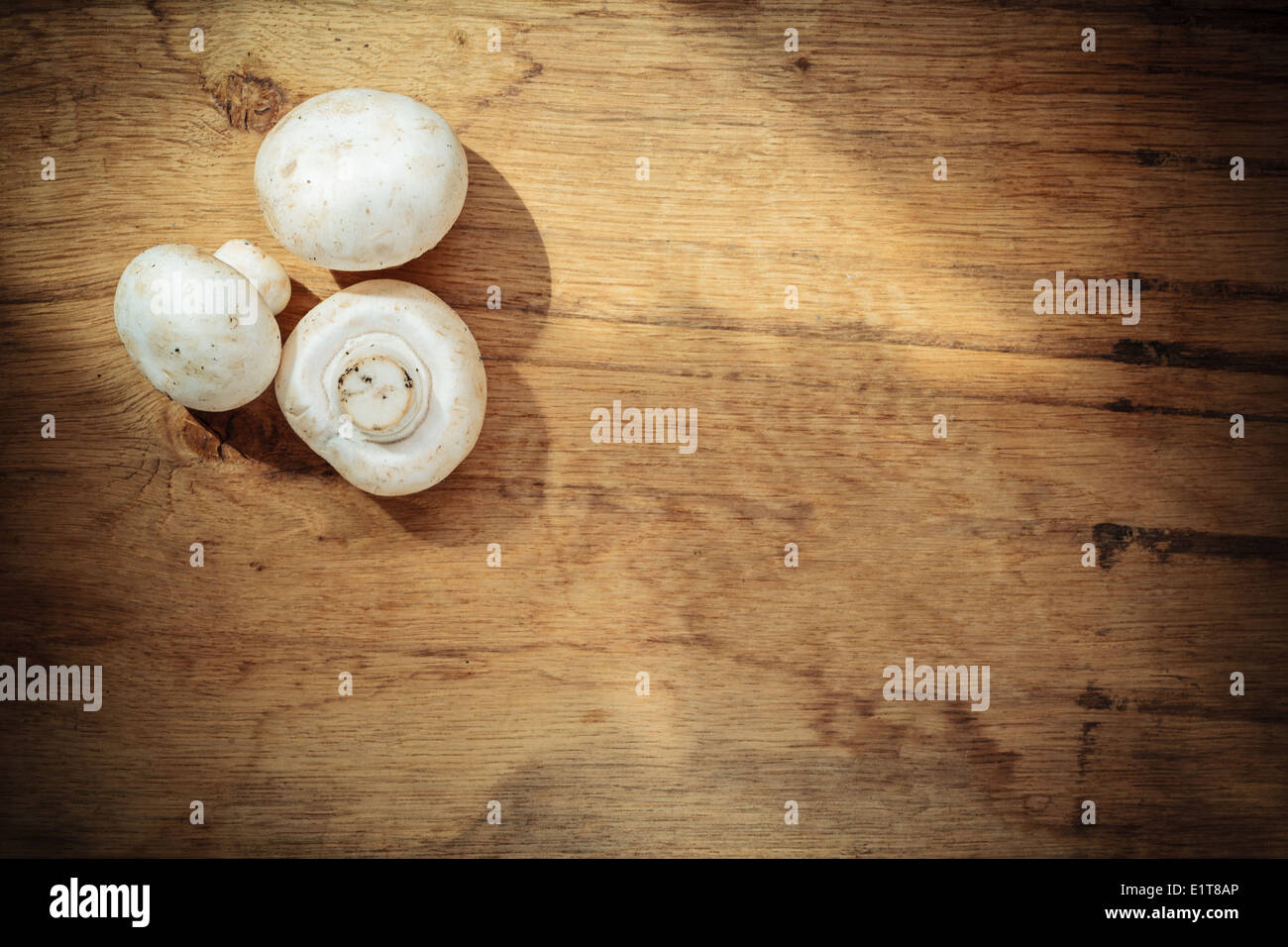 Vegetarian food. Fresh white mushrooms champigonons on wooden kitchen table as background. Stock Photo