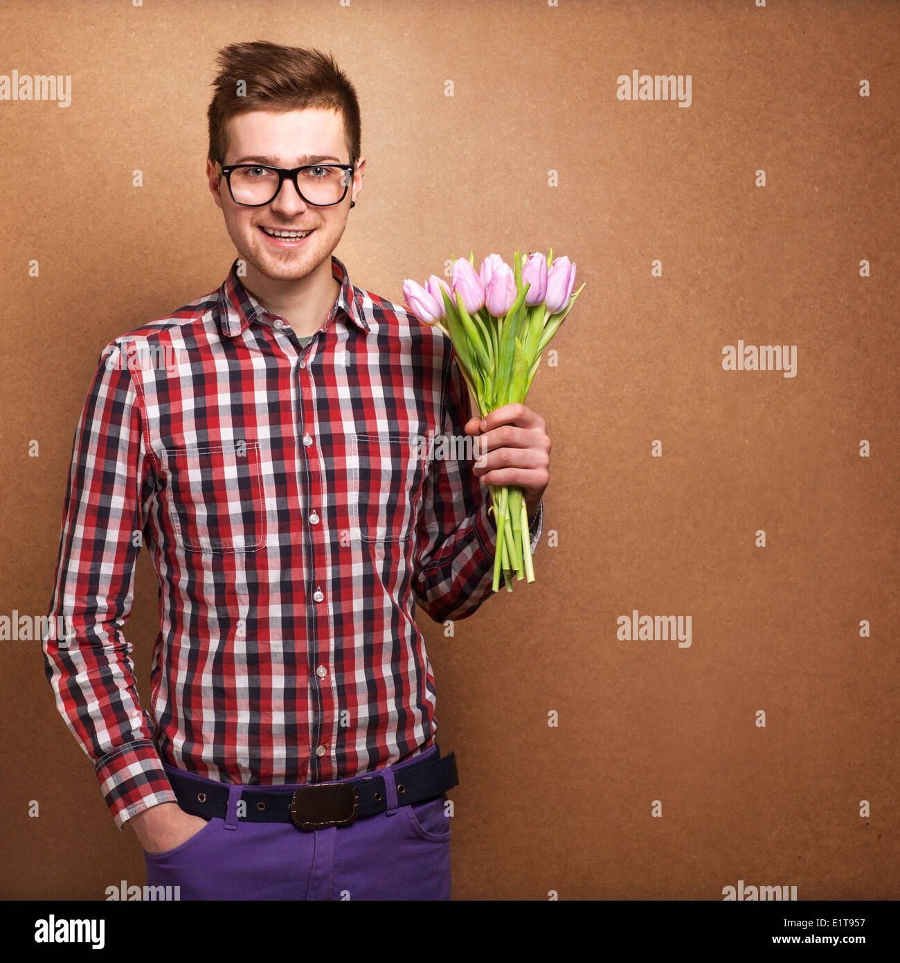 A young romantic man holding a bouquet of flowers isolated on white ...
