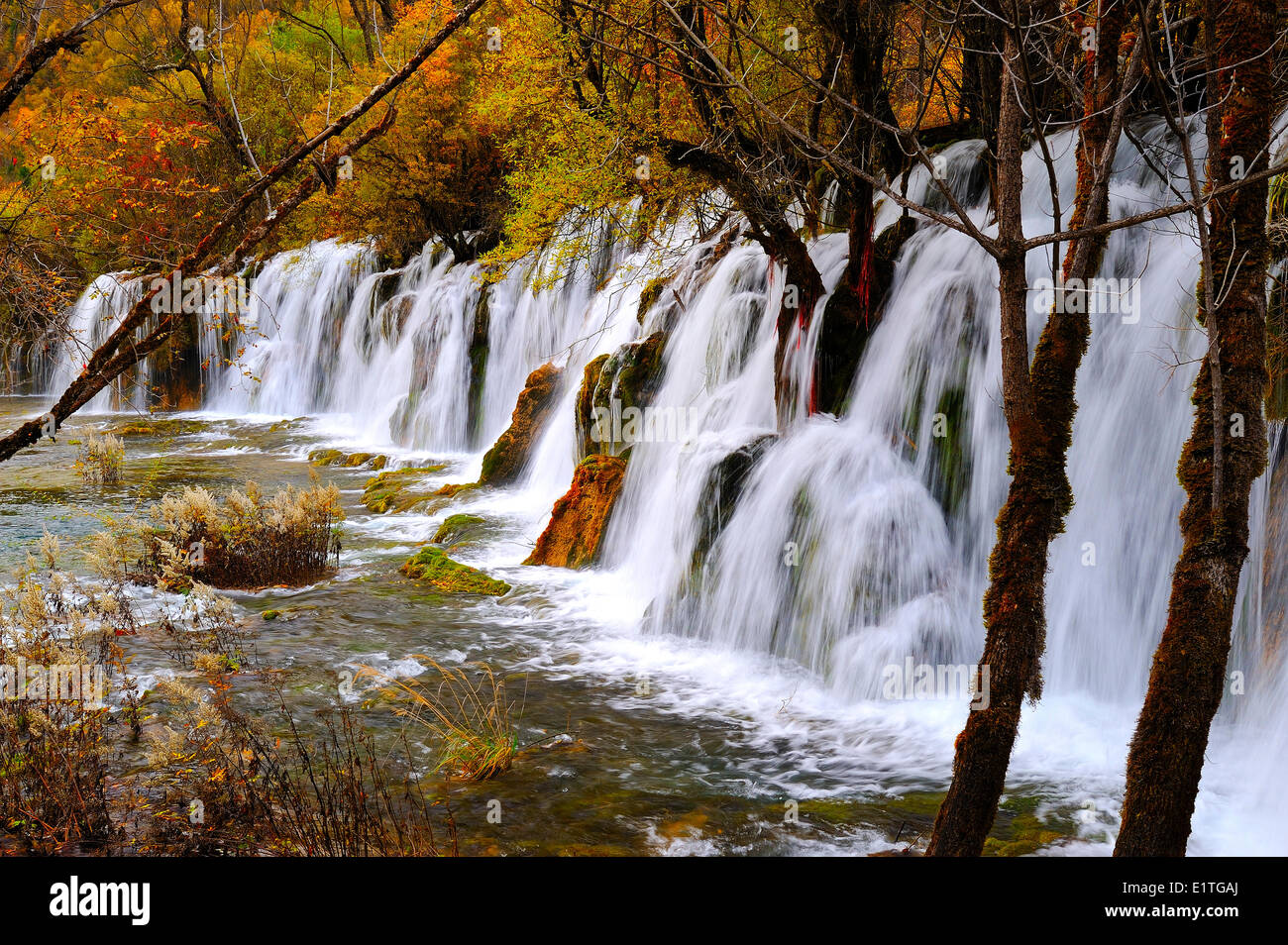 View a freshwater stream with waterfall a walking path in autumn in JiuZhaiGou National Park in Sichuan Province P.R. China. Stock Photo