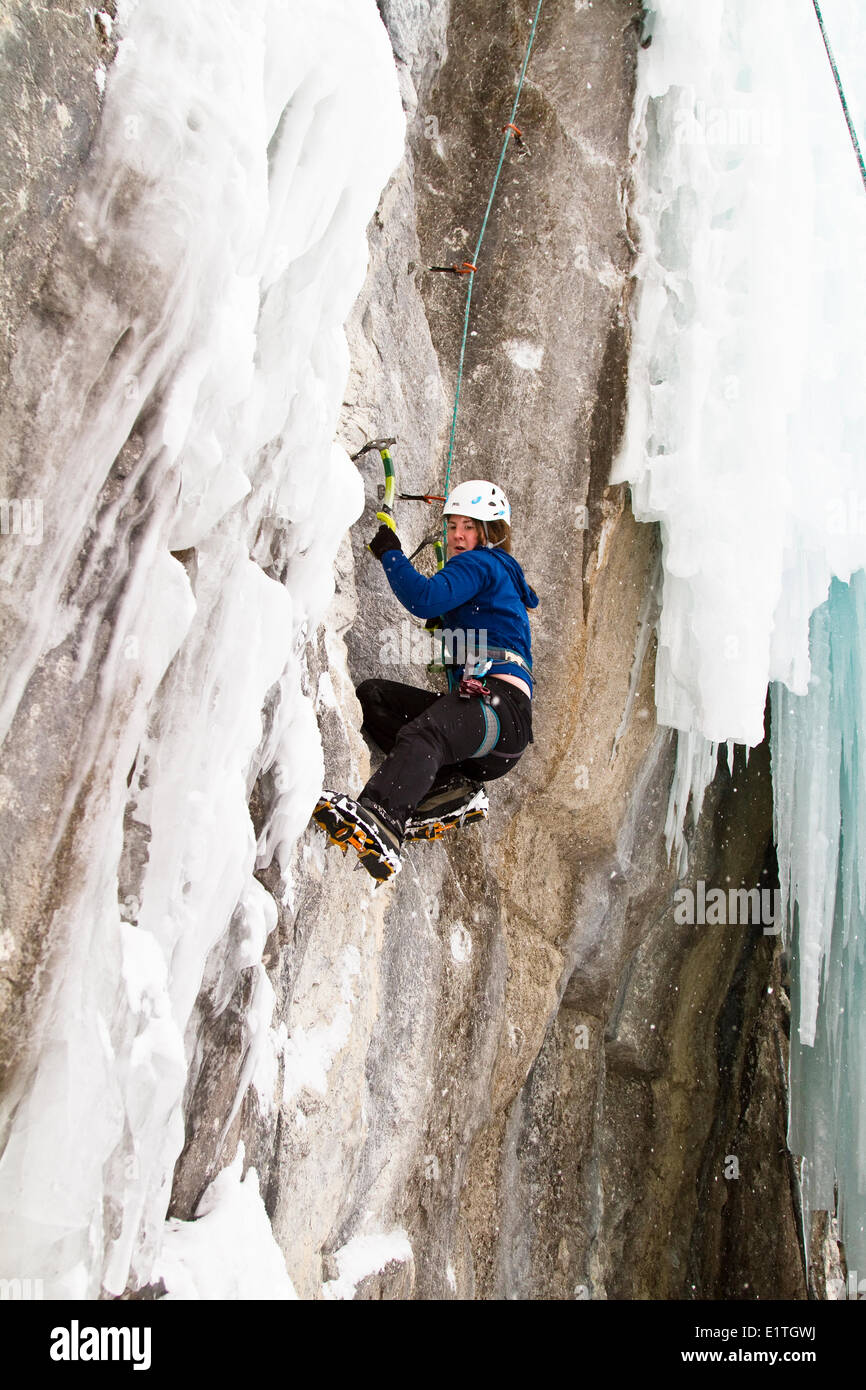 Young woman climbs a mix of ice and rock while iceclimbing in Banff