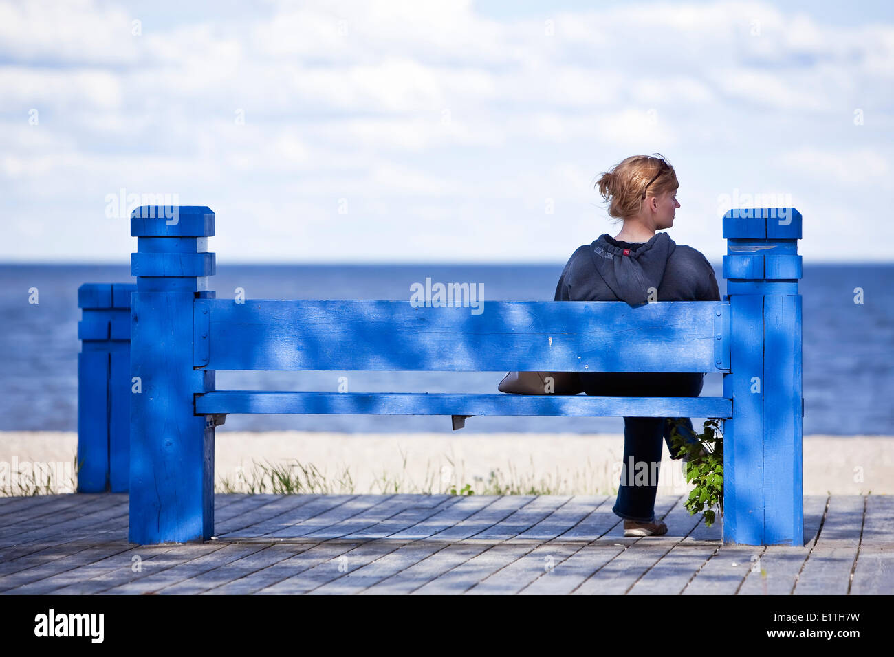 Woman sitting on a blue bench, on Gimli Beach boardwalk, Lake Winnipeg, Gimli, Manitoba, Canada Stock Photo
