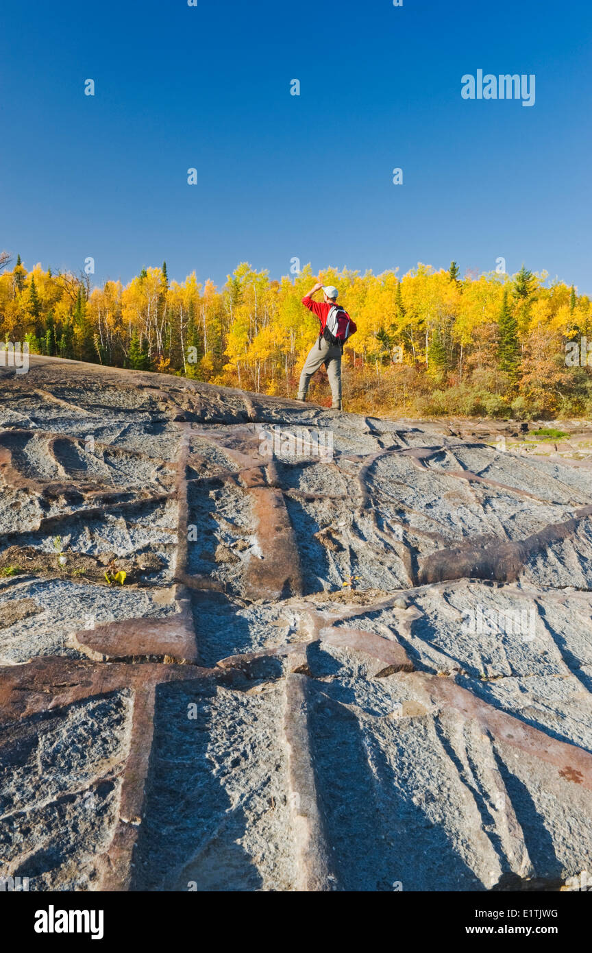 autumn, hiker on precambrian shield rock along the Winnipeg River, near ...