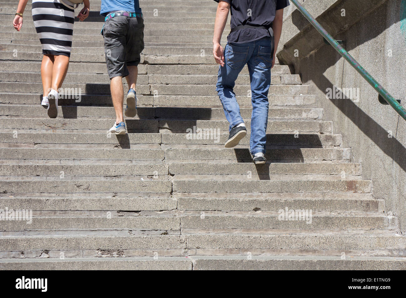 A woman and two man climbing on concrete stairs Stock Photo