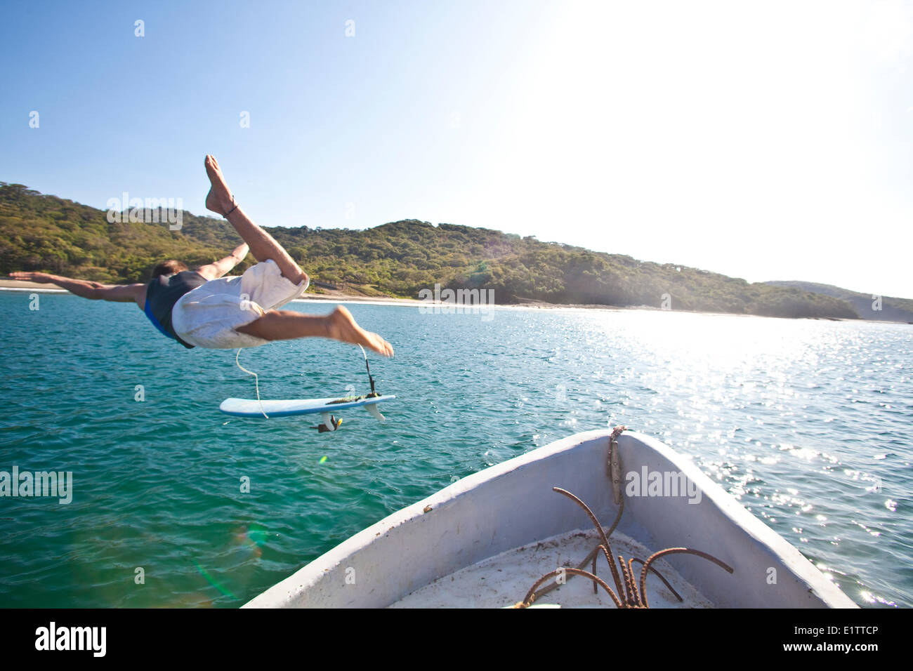A young man jumps off the water taxi to go surf. San Juan del Sur, Nicaragua Stock Photo