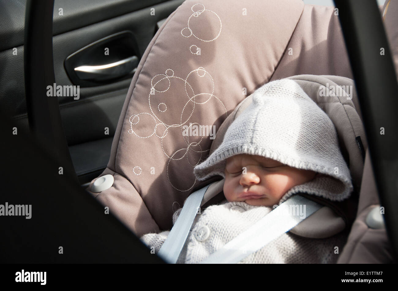 View of a baby sitting in car seat through back door Stock Photo
