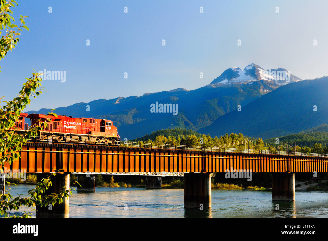 A Canadian Pacific Rail locomotive crosses the rail bridge over the Columbia River in Revelstoke, BC Stock Photo