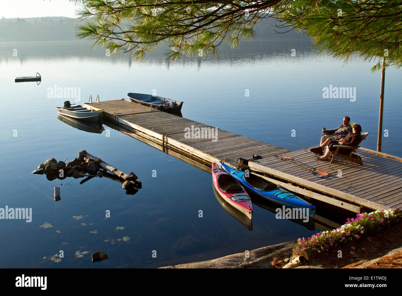 Middle-aged couple enjoy quiet morning on dock near their cottage, Source Lake, Algonquin Park, Ontario, Canada. Stock Photo