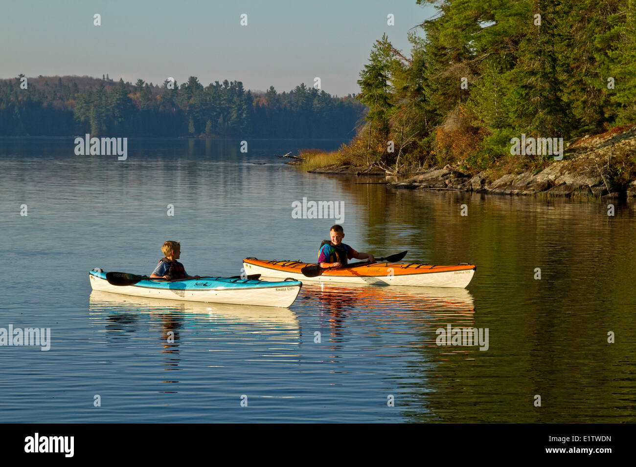 Two young boys enjoy early morning paddle in kayaks on Source Lake, Algonquin Park, Ontario, Canada. Stock Photo