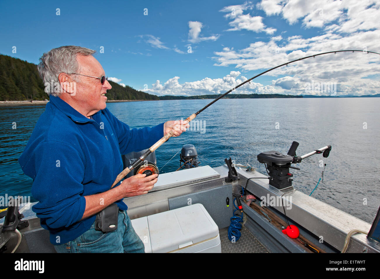 Senior retired man fishing with fishing rod in his hands off Northern Vancouver Island in British Columbia, Canada. Stock Photo