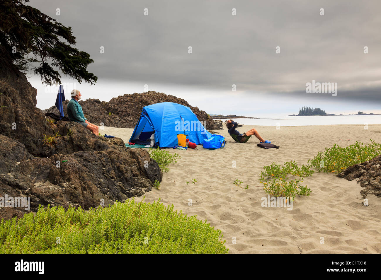 Two kayakers relax at their campsite on Whaler Islet off the British Columbia coast, Canada. Model Released Stock Photo