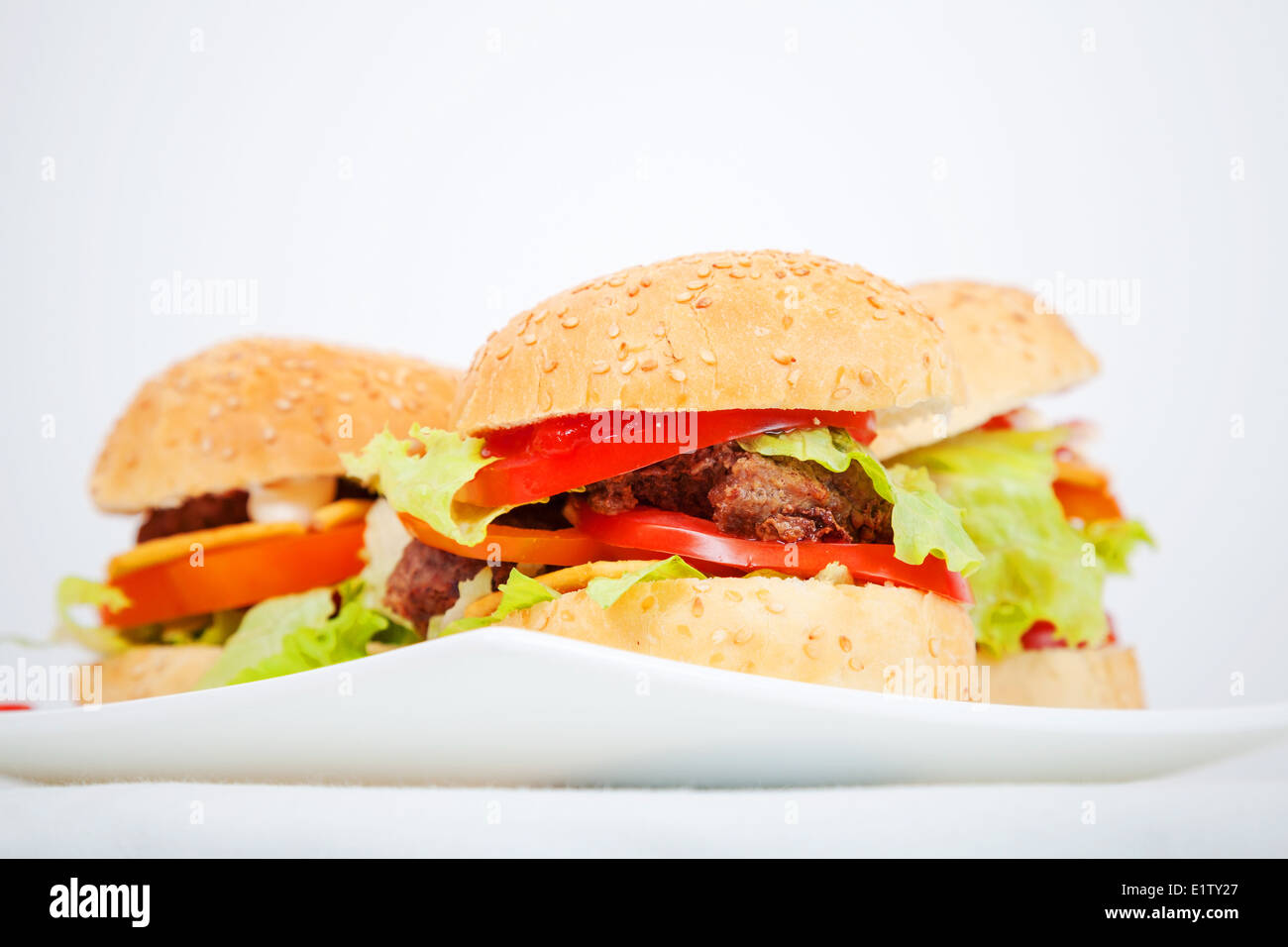 Big homemade hamburgers lay on white plate Stock Photo