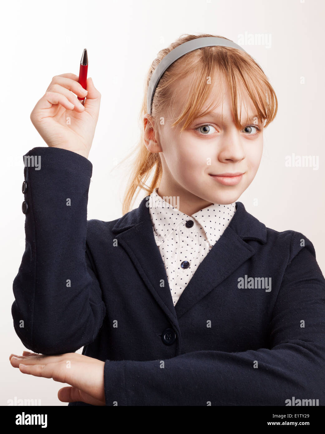 Little blond schoolgirl holds up the pen Stock Photo