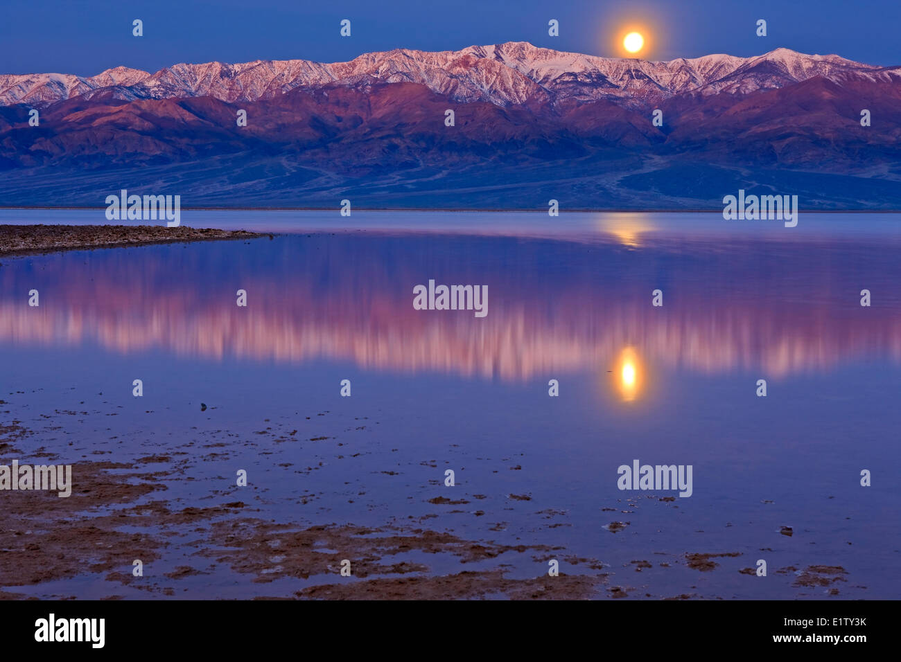 Reflections in Badwater Basin lake Moonrise over Panamint Mountains Badwater Basin Death Valley National Park California USA Stock Photo