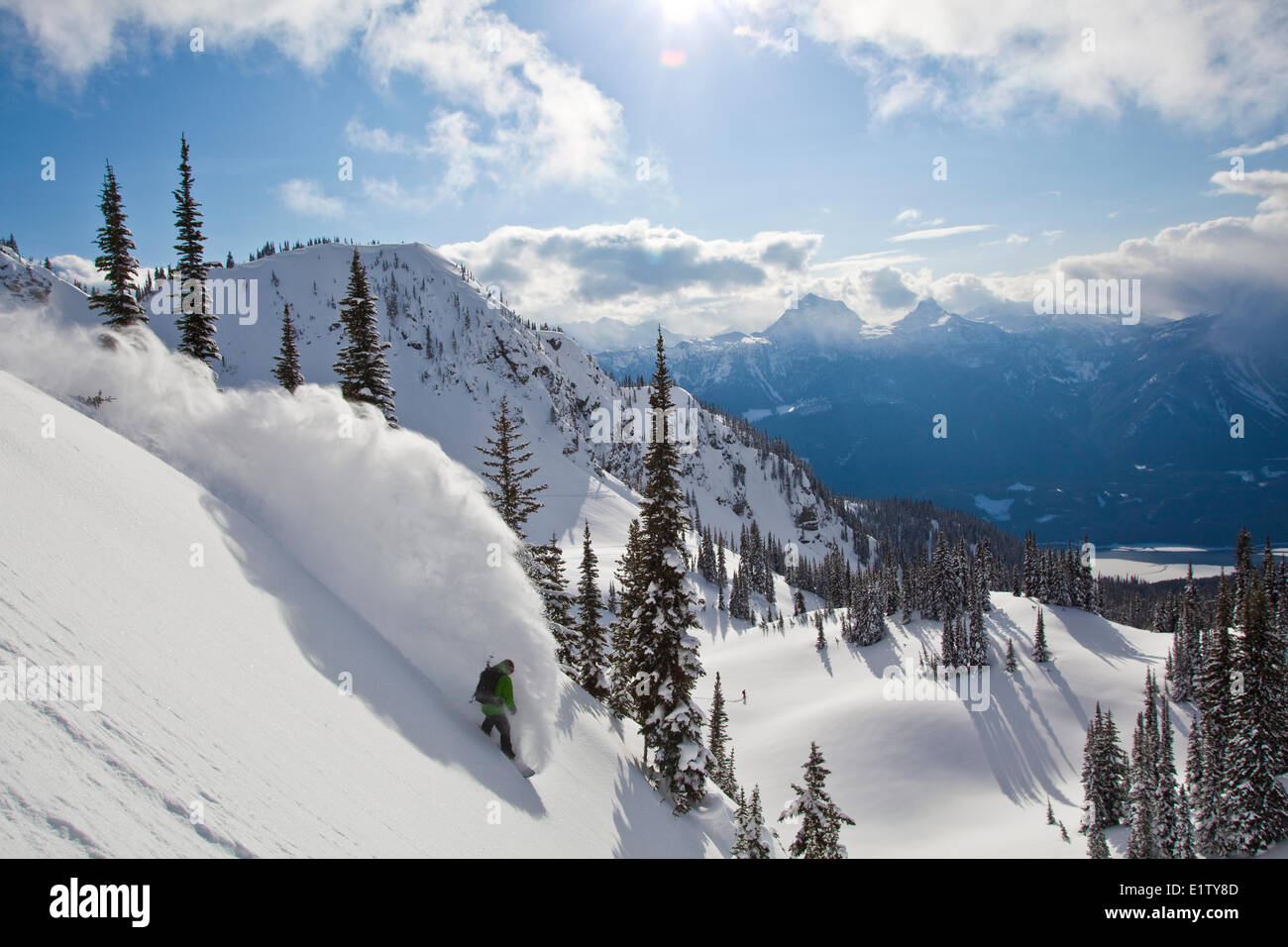 A male backcountry snowboarder sprays some powder in the Revelstoke Mountain Backcountry, BC Stock Photo
