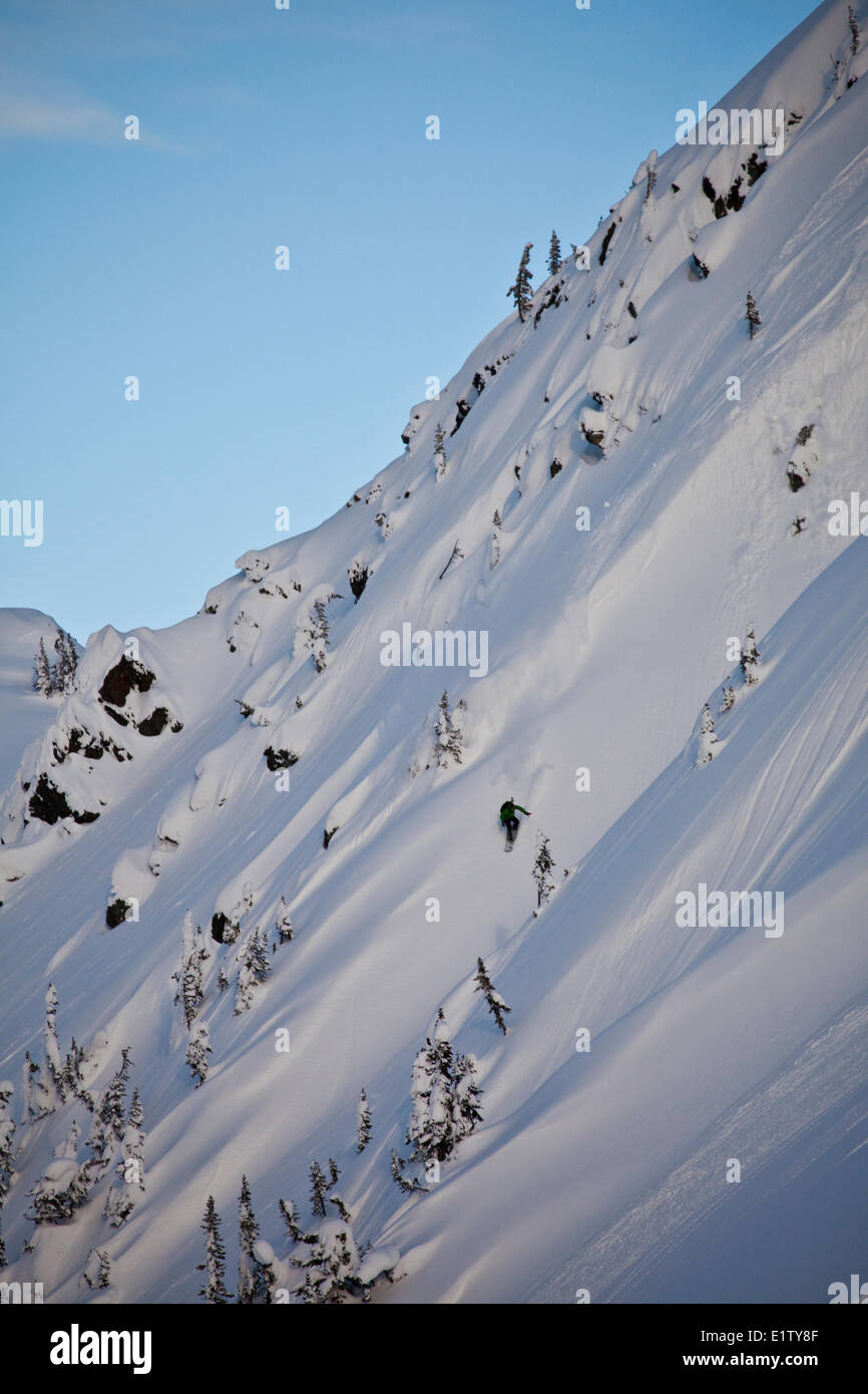 A male backcountry snowboarder sprays some powder in the Revelstoke Mountain Backcountry, BC Stock Photo