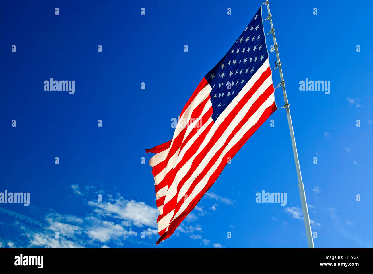 The american flag waving in the wind on a clear blue sky day. Stock Photo