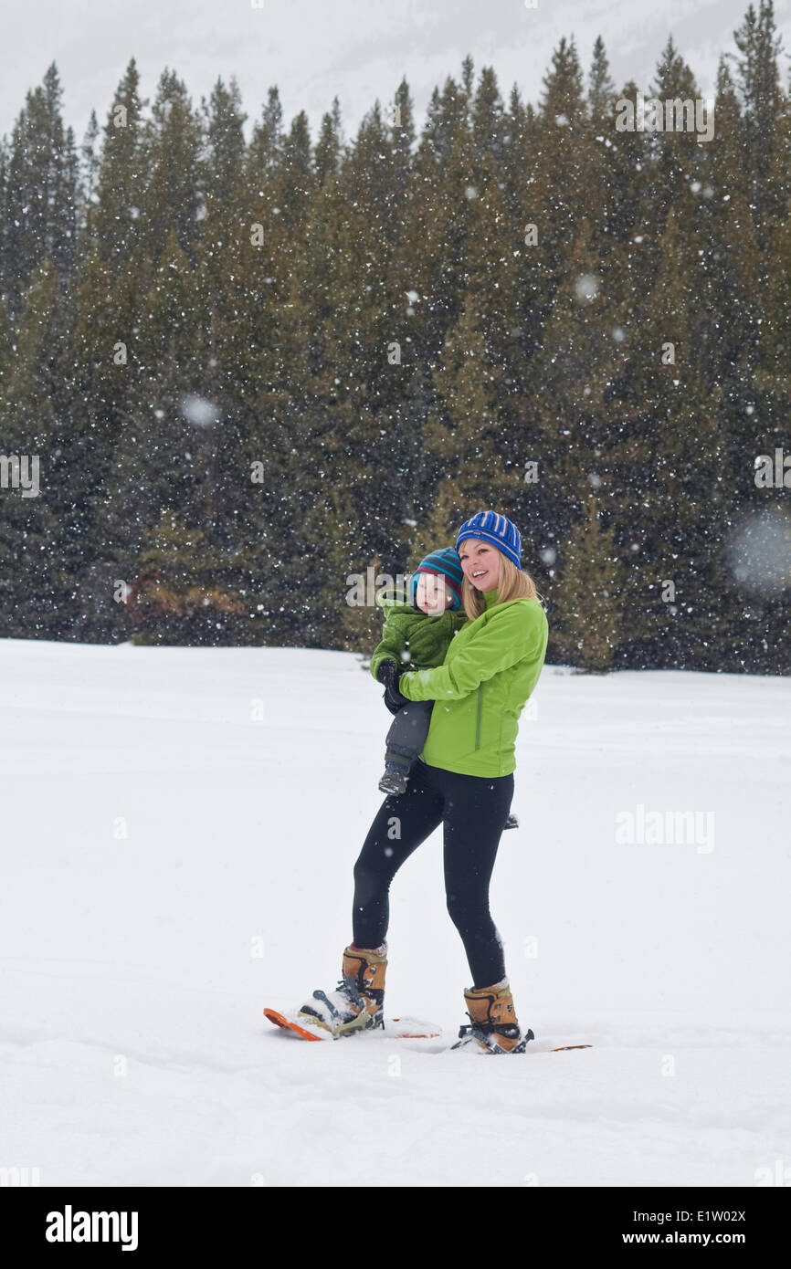 A young mother and baby son snowshoeing in Poccaterra, Peter Lougheed Park, Kananaskis, AB Stock Photo