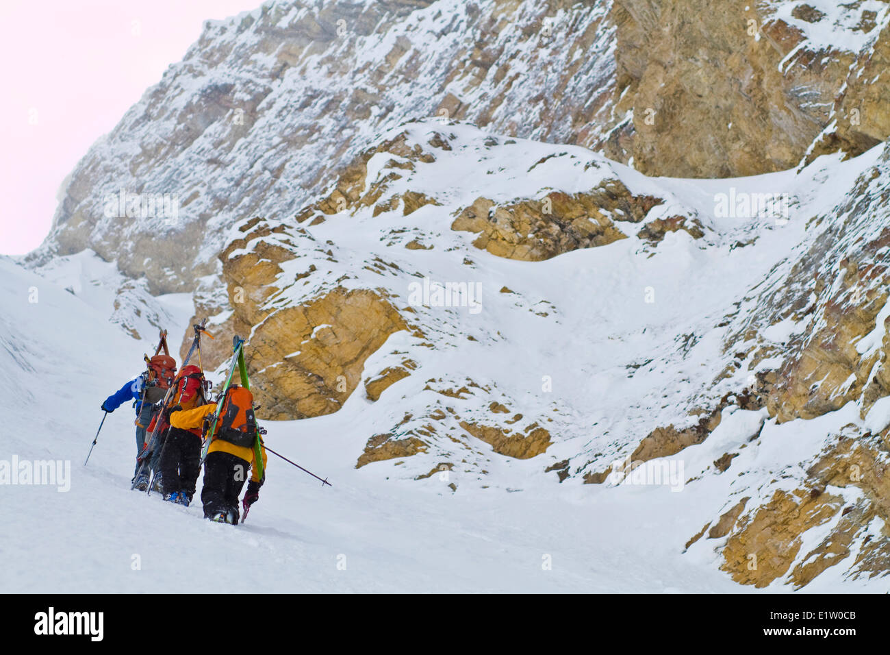 Three male backcountry skiers bootpack up a steep and committing line on Mt. Chester, Kananaskis, AB Stock Photo