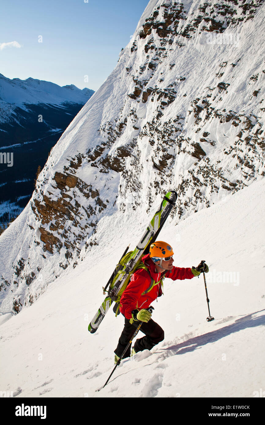 A male backcountry skier bootpacks up a steep and exposed coulior on Mt. Patterson, Icefields Parkway, Banff, AB Stock Photo