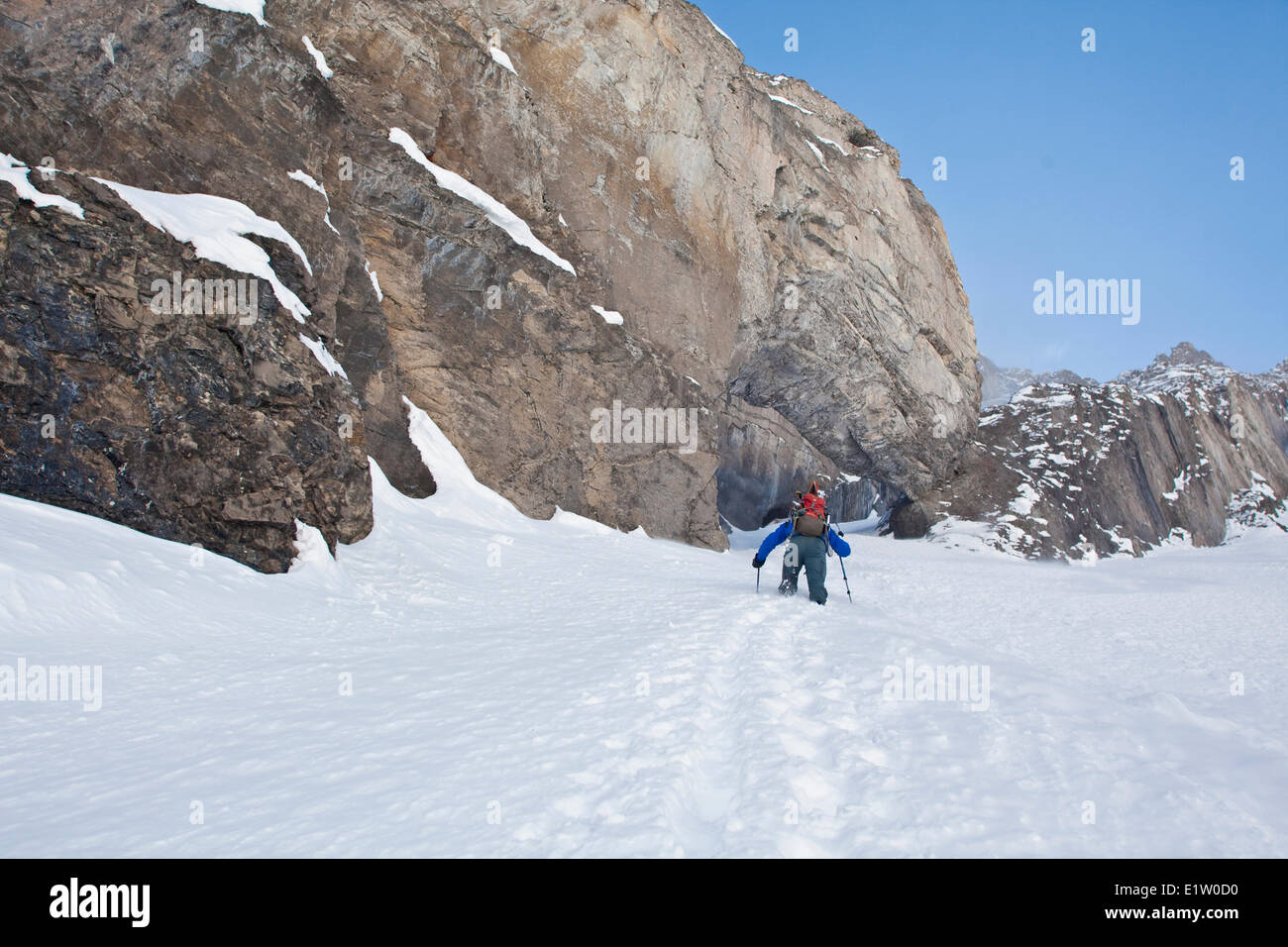 A male backcountry skier bootpacks up a steep couloir with a unique limestone arch in it. Mt. French Peter Lougheed Provincial Stock Photo