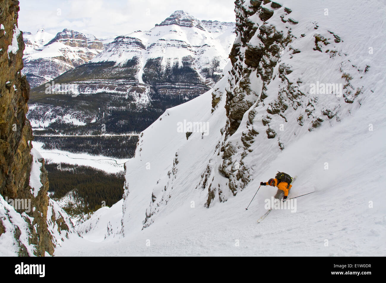 A male backcountry skier on tele skis drops into a steep couloir along the Icefields Parkway, Banff National Park,  AB Stock Photo