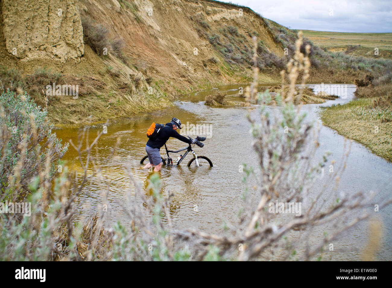 A man pushes his mountain bike through spring run off conditions on the Maah Daah Hey Trail, North Dakota Stock Photo
