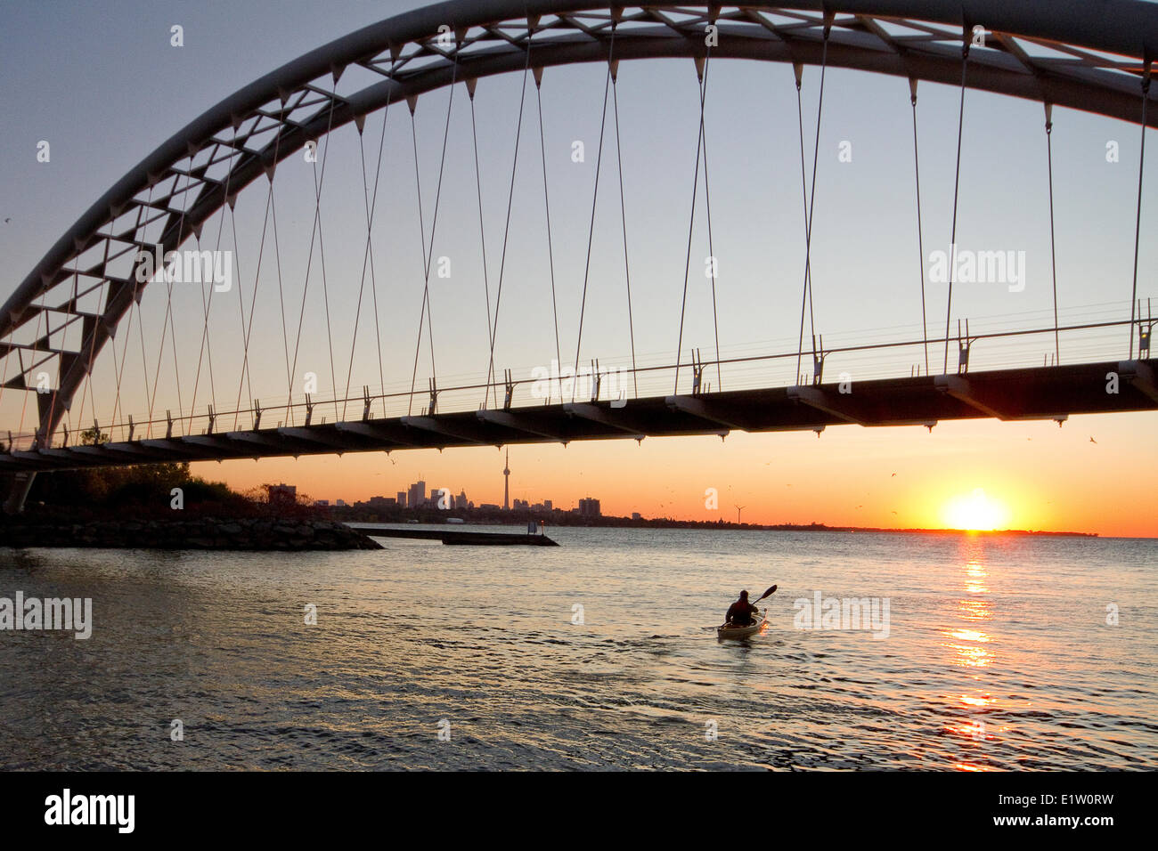 Young man paddling kayak under Humber River Arch Bridge on Lake Ontario, Toronto, Ontario, Canada. Stock Photo