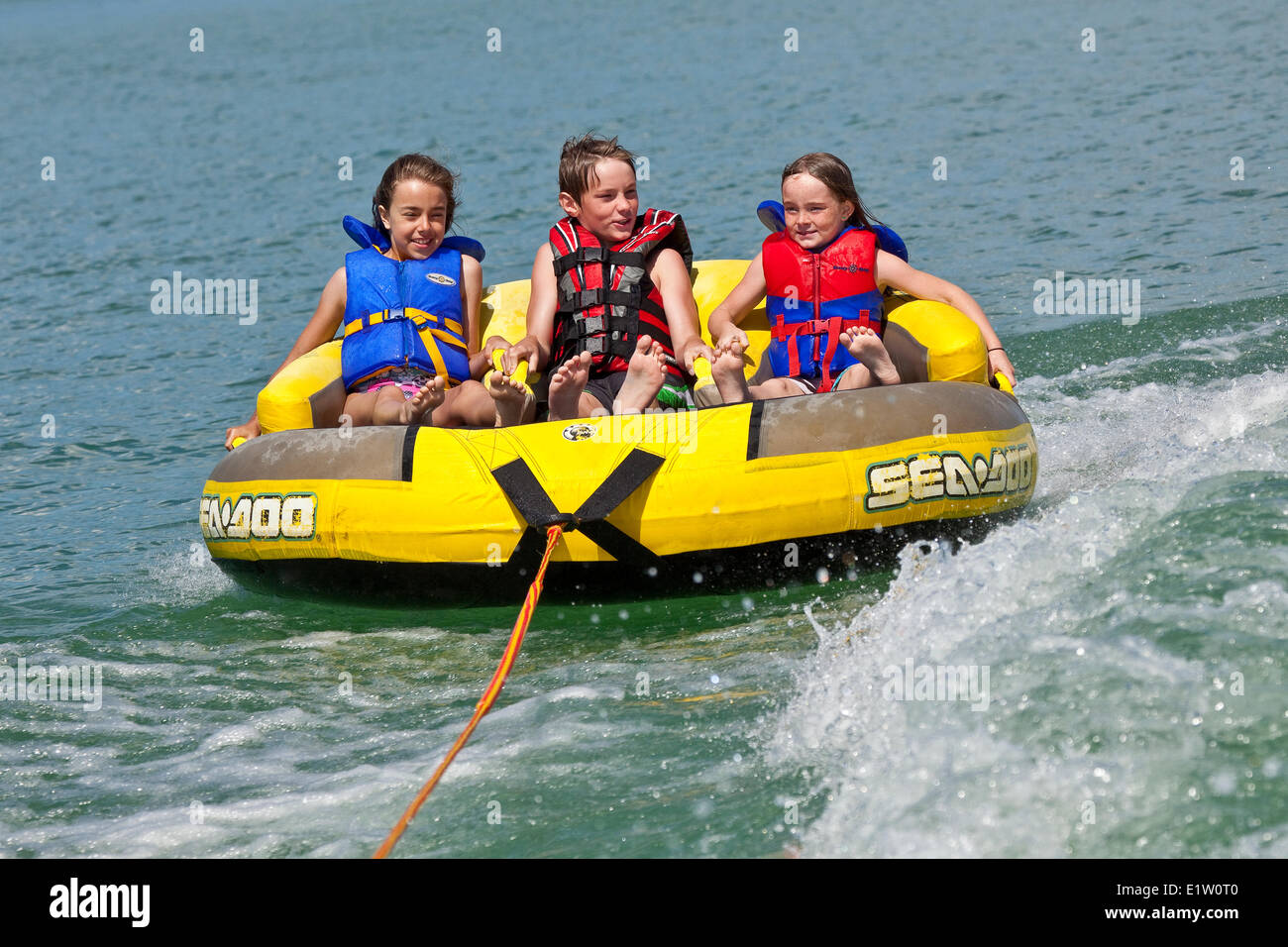 Three children enjoy tubing on Lake Koocanusa, East Kootenays, BC, Canada. Stock Photo