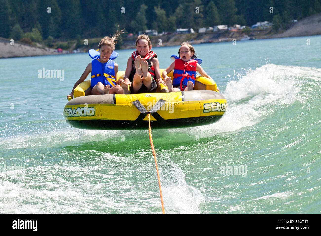 Three children enjoy tubing on Lake Koocanusa, East Kootenays, BC, Canada. Stock Photo