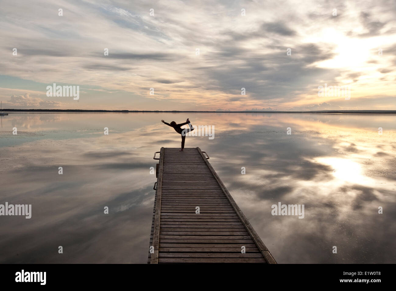 Young girl practises yoga on dock on Cardinal Lake, Queen Elizabeth Provincial Park, Alberta, Canada. Stock Photo