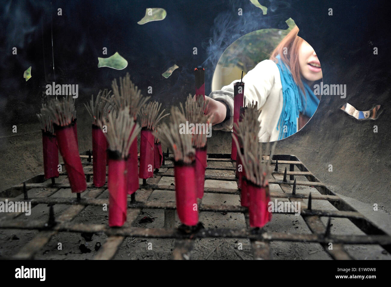 Japanese woman placing incense in the burner at Kotokuin by the statue of Great Buddha in