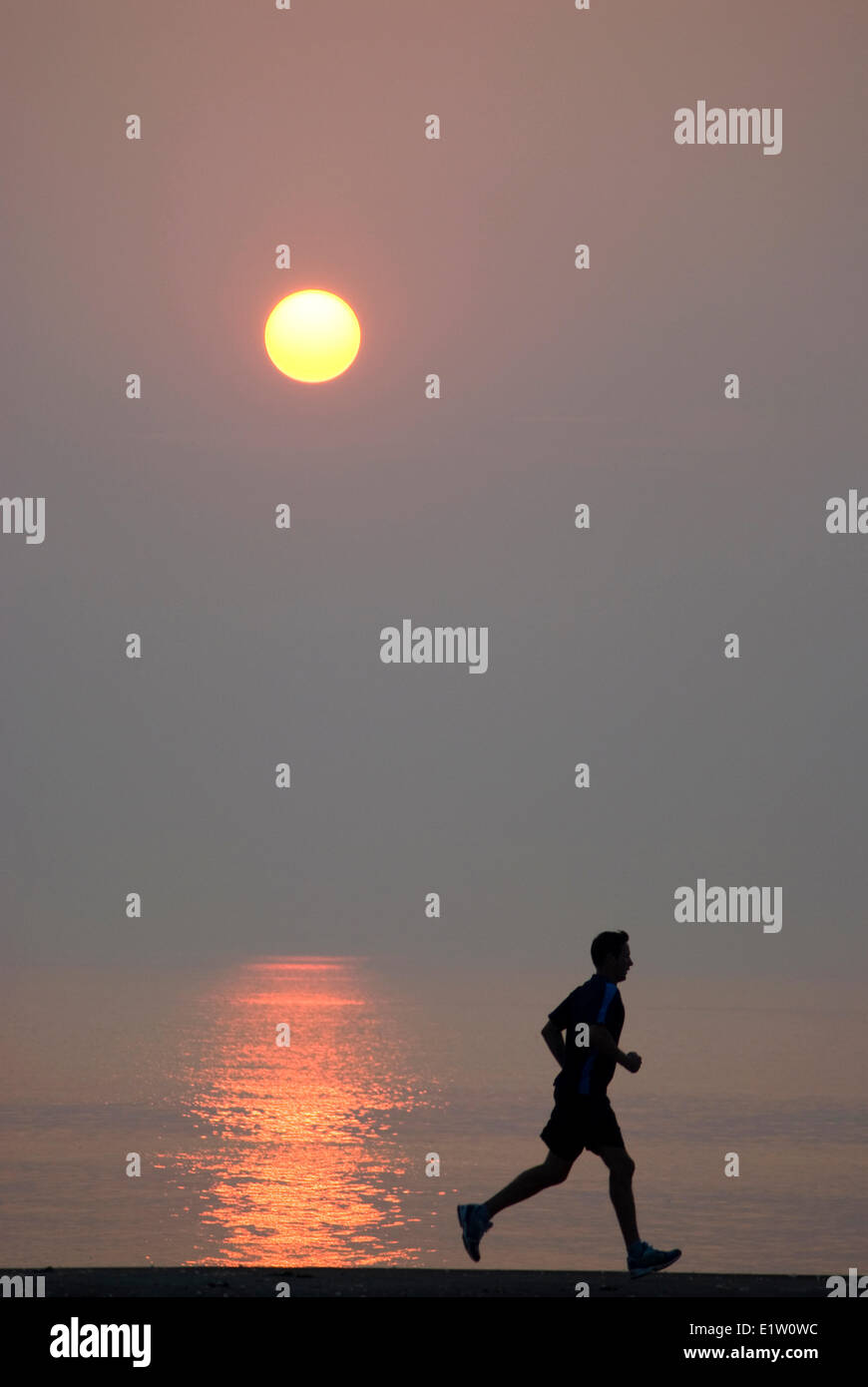 Man jogging at sunrise on a pier in Oakville, Ontario Stock Photo