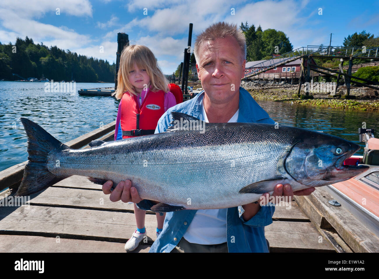 Proud fisherman with 24 pound chinook salmon and unimpressed daughter. Stock Photo