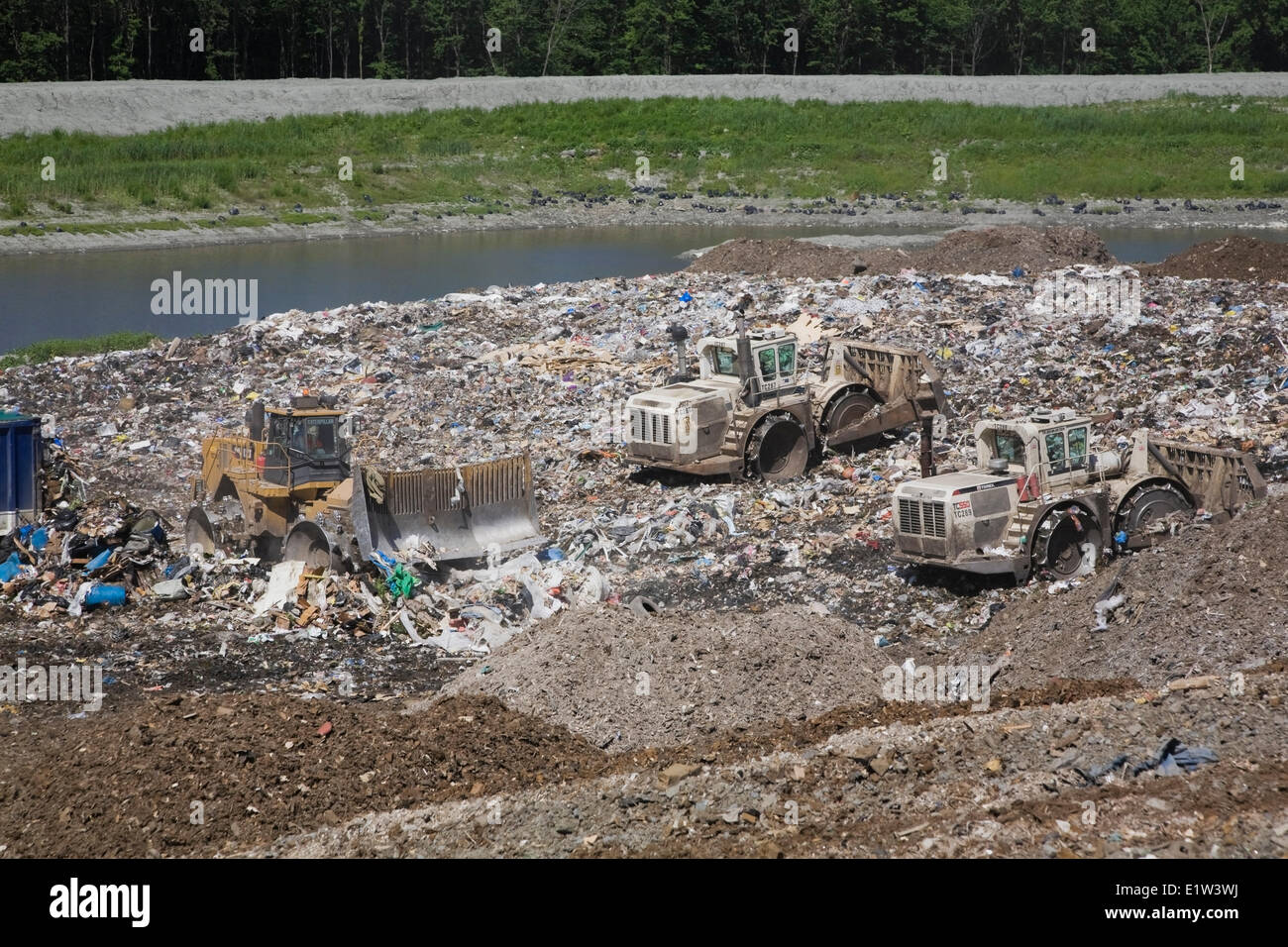 Heavy machinery spreading out and compacting discarded debris and trash at a waste management site, Quebec, Canada Stock Photo
