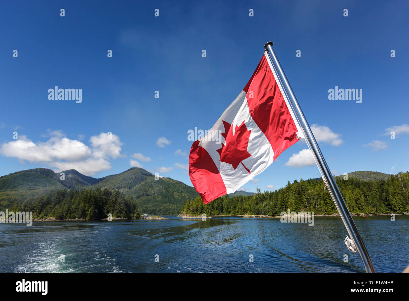 The Canadian Flag flies from the stern of the Uchuck 111 as it traverses Esperanza Inlet, British Columbia, Canada. Stock Photo