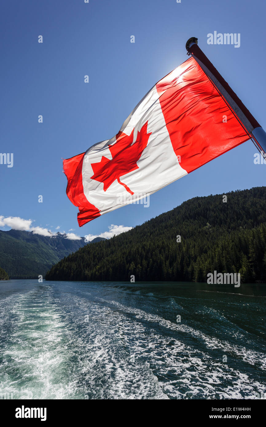 The Canadian Flag flies from the stern of the Uchuck 111 as it traverses Esperanza Inlet, British Columbia, Canada. Stock Photo