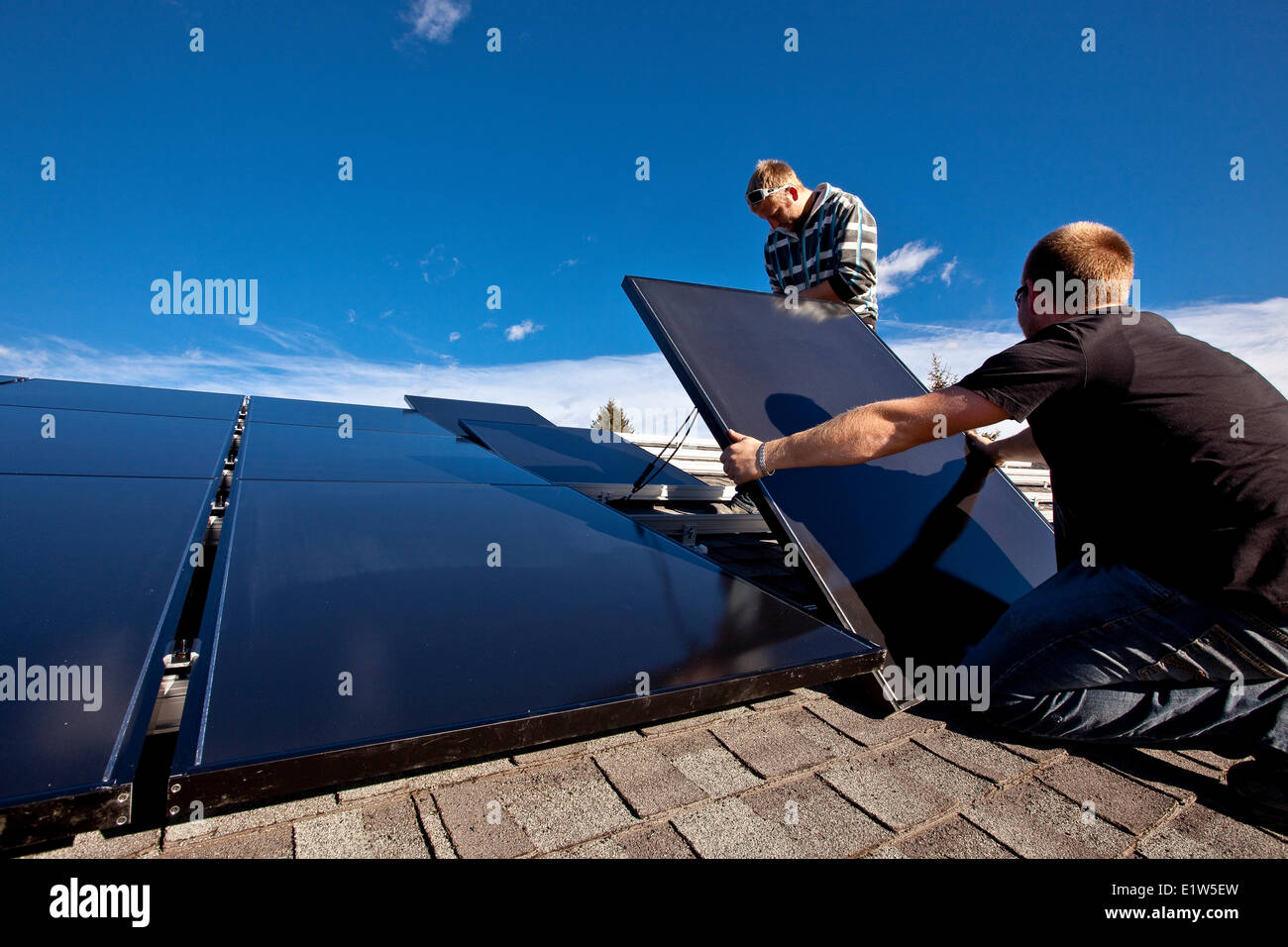 Two solar panel installers install solar panels on roof, Alberta