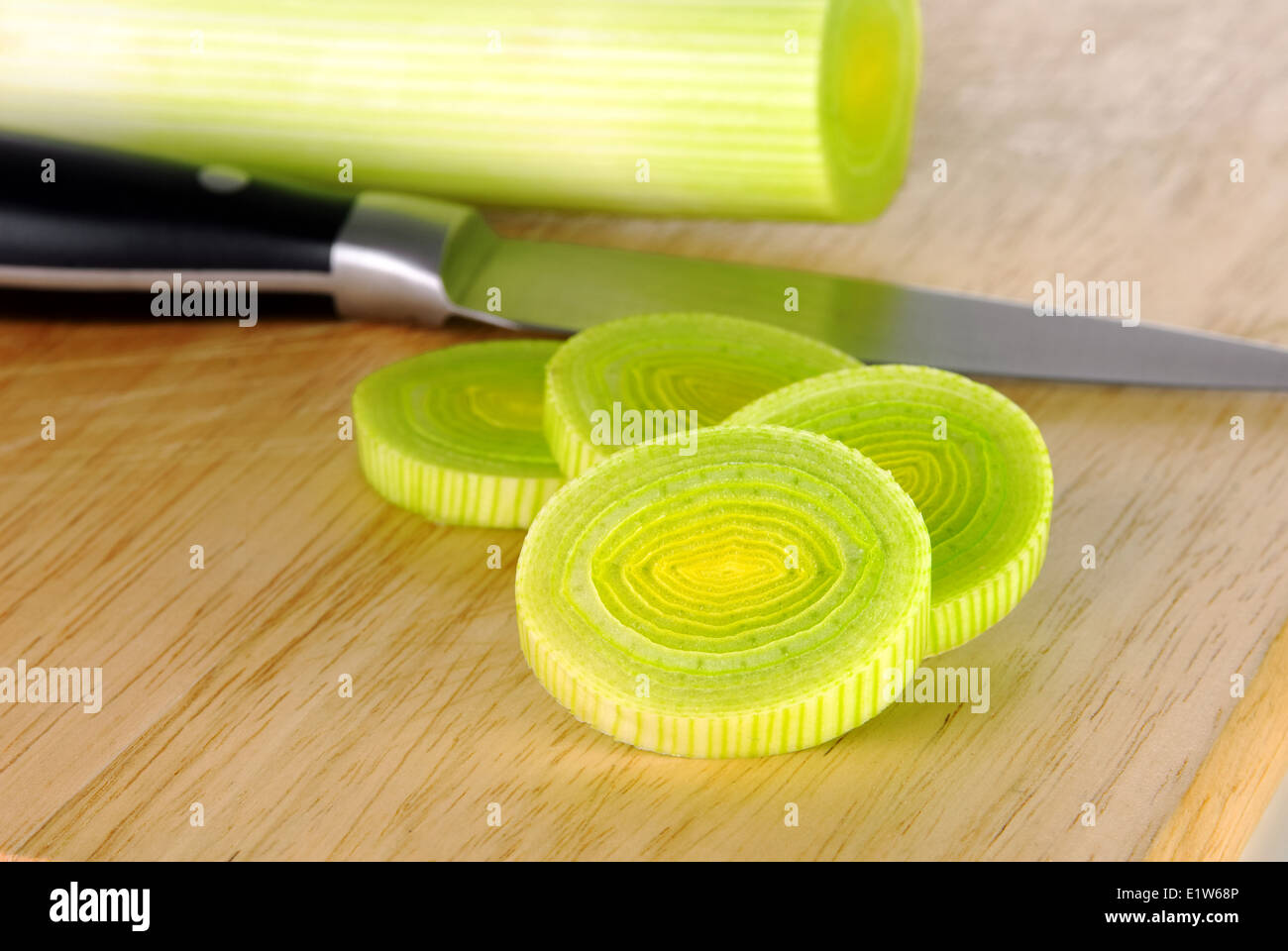 Fresh leek whole and sliced on a wooden board with knife Stock Photo